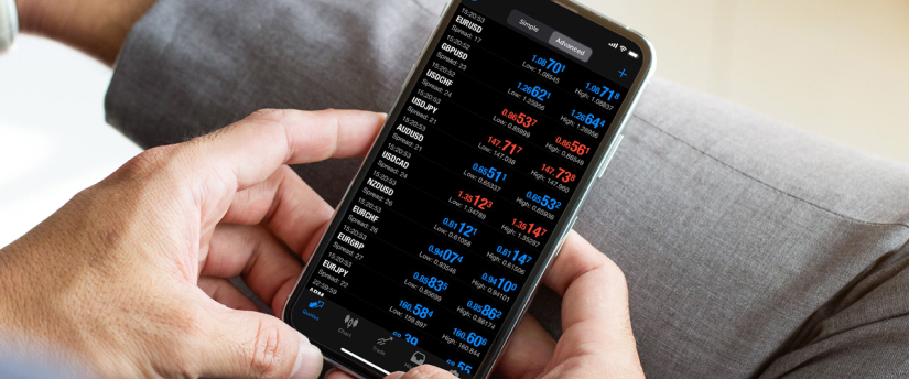 Une personne effectuant des opérations boursières sur un iPhone, dont l'écran affiche des mises à jour en temps réel et des informations financières.