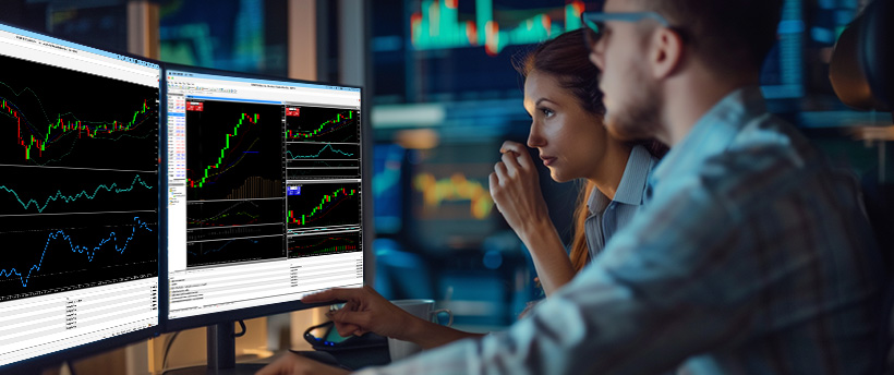 Dos traders de forex analizando datos de trading en la pantalla de un ordenador, centrados en la psicología del trading y las tendencias del mercado
