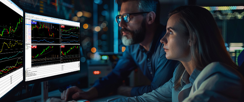 Two individuals observing trading data on screens, emphasizing the psychological factors influencing their trading strategies.
