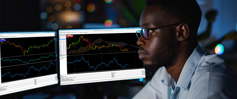 Trader comparing a price chart with an oscillator indicator on two screens